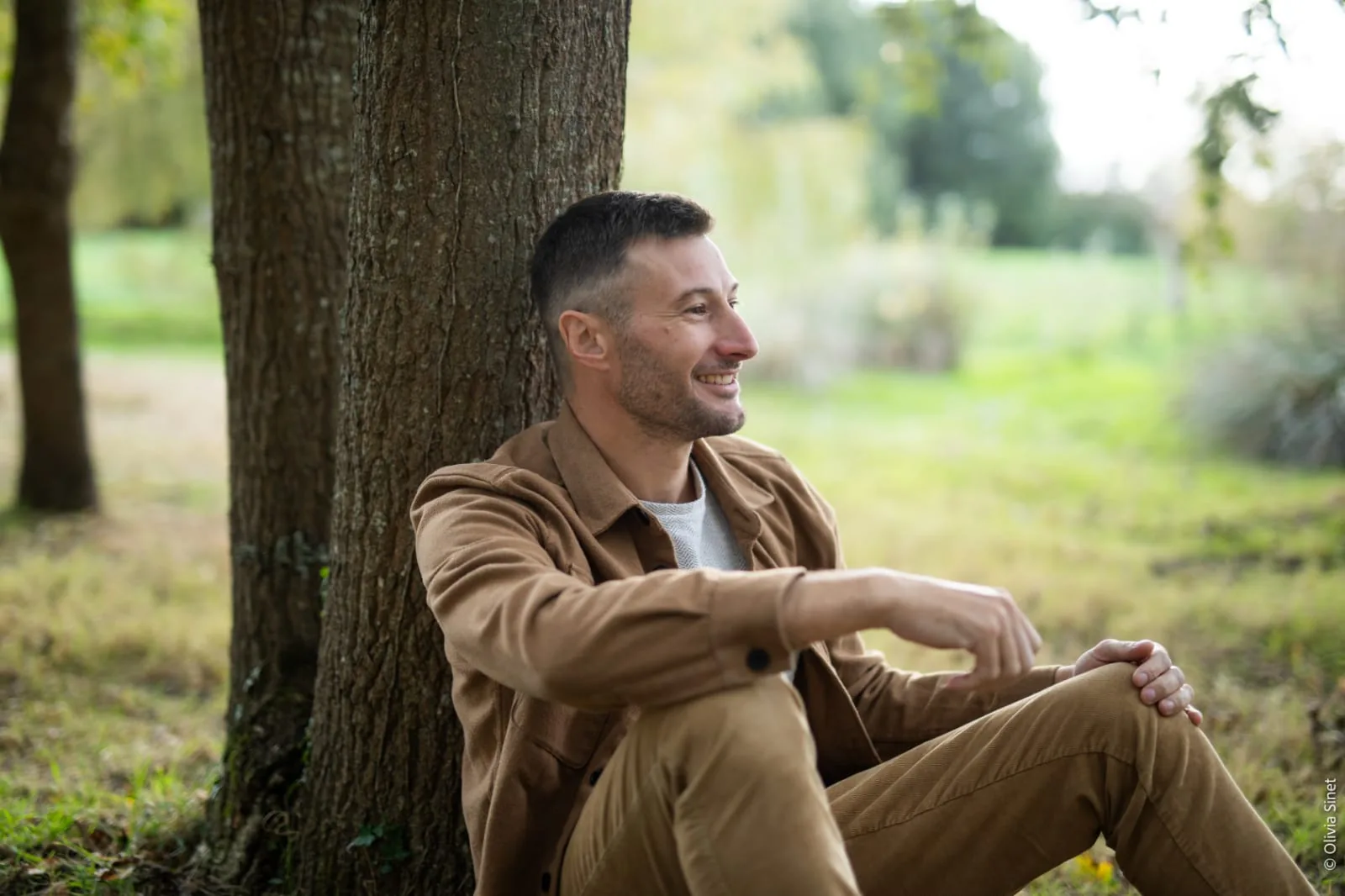 Damien Doussot assis au pied d'un arbre, dans la nature